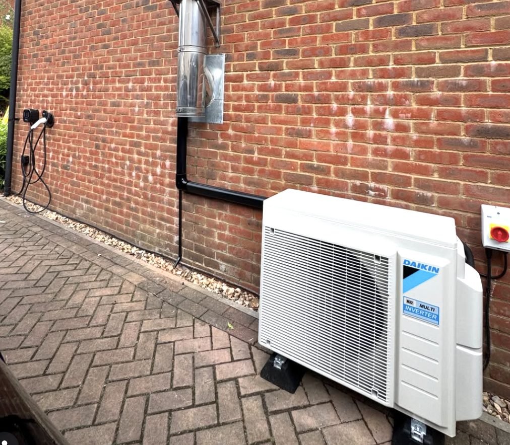 Daikin multi-split inverter outdoor unit installed at ground level beside a brick wall